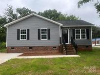 Charming home with gray siding, black shutters, brick foundation and landscaped front yard at 506 Locust St, Rock Hill, SC 29730