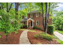 Charming brick home featuring a manicured front yard with mature trees and a walkway to the entrance at 626 Trail Ridge Rd, Matthews, NC 28105