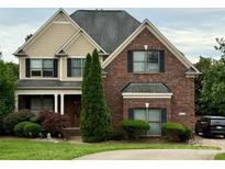 Charming brick two-story home with manicured lawn, black shutters, and mature trees at 8620 Rolling Fields Rd, Charlotte, NC 28227