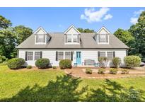 Charming single-Gathering home featuring a bright blue front door, complemented by a well-manicured lawn and lovely landscaping at 118 Grain Dr, Stony Point, NC 28678