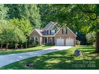 Charming brick home featuring an attached two-car garage, well-manicured lawn, and long driveway at 122 Ardmore Pl, Mooresville, NC 28117
