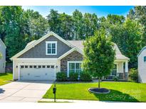 Charming home featuring a manicured lawn, two-car garage, and a mix of stone and gray plank exterior accents at 14727 Brannock Hills Dr, Charlotte, NC 28278