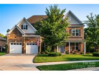 Charming brick home featuring a manicured lawn, two-car garage, and welcoming front porch at 159 Holly Ridge Dr, Mooresville, NC 28115