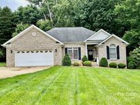 Charming brick home featuring a well-manicured lawn and a two-car garage at 35 Wittenburg Springs Dr, Taylorsville, NC 28681