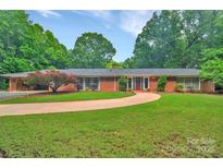 Charming brick home features a well-manicured lawn, mature trees, and a circular driveway, offering classic curb appeal at 514 Wood St, Troy, NC 27371