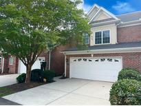 Brick two-story home with a white garage door, mature trees, and manicured landscaping create great curb appeal at 705 Congressional Ln, Fort Mill, SC 29708