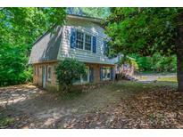 An exterior view of a home with gray and white siding, blue shutters, and surrounded by lush, mature trees at 7320 Ritter Dr, Charlotte, NC 28270