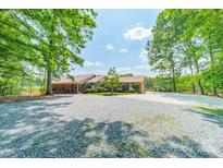 Charming ranch-style home with a spacious gravel driveway and mature trees, creating a serene and inviting atmosphere at 12705 Caldwell Rd, Charlotte, NC 28213