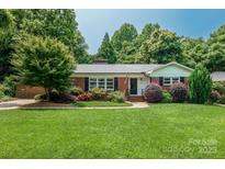 Charming brick home with a lush green lawn, mature trees, and manicured landscaping at 1619 Flynnwood Dr, Charlotte, NC 28205