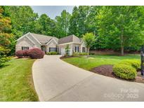 Charming brick home featuring a well-manicured lawn, mature trees, and a long driveway leading to the garage at 16527 Woolwine Rd, Charlotte, NC 28278