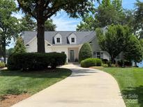 Charming, white home featuring a circular drive, manicured lawn and beautiful mature trees at 17719 Springwinds Dr, Cornelius, NC 28031