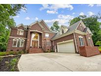 A grand two-story red brick home featuring a manicured lawn, a two car garage, and a concrete driveway at 3324 Greenhurst Dr, Matthews, NC 28104