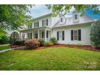 Traditional two-story home featuring a welcoming front porch, mature landscaping, and classic black shutters at 506 Academy St, McAdenville, NC 28101