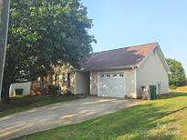 Charming single-story home with a manicured lawn, mature tree, and attached one car garage at 6902 Vernon Wood Ln, Charlotte, NC 28262