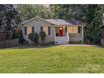Charming one-story home features a freshly cut lawn and a bright red front door at 6935 Woodstock Dr, Charlotte, NC 28210
