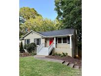 Charming single-story home with a red door, a well-manicured lawn, and front yard landscaping at 6935 Woodstock Dr, Charlotte, NC 28210