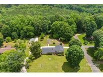 An aerial view displays a home with a lush green lawn surrounded by trees, and a detached garage at 111 Kelly Ln, Gastonia, NC 28056