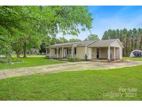 Inviting single story home boasts a long driveway, attached covered parking, and well-maintained front yard with mature trees at 1116 Crestview Dr, Salisbury, NC 28146