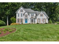 Beautiful two-story white brick home with a manicured lawn, bright blue front door, and mature landscaping at 122 Ringneck Trl, Mooresville, NC 28117