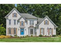 Elegant, two-story brick home features a bright blue front door, manicured lawn, and mature trees at 122 Ringneck Trl, Mooresville, NC 28117