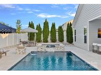 Beautiful backyard pool with travertine tile, water feature, and outdoor dining area, perfect for entertaining at 12615 Es Draper Dr, Huntersville, NC 28078