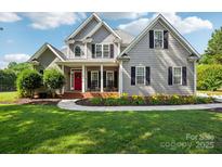 Charming two-story home with a landscaped yard, red door, and inviting front porch at 175 Turnberry Ln, Mooresville, NC 28117