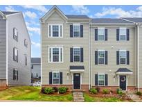 Charming two-story townhouse features a well-maintained lawn, brick accents, and classic black shutters, creating curb appeal at 2203 Autumn Olive Ln, Stallings, NC 28104
