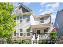 Charming two-story home featuring stone accents, a welcoming front porch, a fenced yard, and a US flag at 635 R L Stowe Rd, Belmont, NC 28012