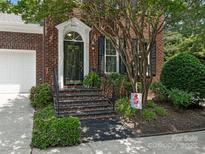 Charming brick home showcasing a stylish front door, black shutters, and lush landscaping at 9451 Bonnie Briar Cir, Charlotte, NC 28277