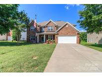 Charming two-story brick home featuring a two-car garage and well-manicured front lawn at 1006 Apogee Dr, Indian Trail, NC 28079