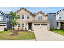 Charming tan two-story home featuring a two-car garage, landscaped yard, and inviting front entrance at 13140 Sudwick Ln, Charlotte, NC 28278