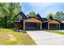 A striking two-story home with a modern design, featuring a black garage door and wooden accents at 1528 Enochville Rd, Kannapolis, NC 28081