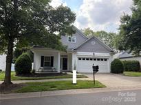 Charming home featuring white siding, a two-car garage, well-manicured landscaping and a cozy front porch at 18715 Coachmans Trce, Cornelius, NC 28031