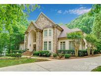 Stunning stone-clad home with lush landscaping, mature trees, and a welcoming entrance creating great curb appeal at 517 Kingsdown Ct, Waxhaw, NC 28173