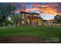 Stunning two-story home with stone accents, manicured lawn, and vibrant sunset backdrop at 639 Edgemont Rd, Charlotte, NC 28211