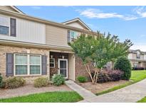 Charming townhome entrance featuring a brick facade, landscaped garden, and well-lit pathway at 6834 Creft Cir, Indian Trail, NC 28079