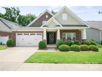 Charming single-Gathering home featuring a two-car garage, brick facade, landscaped yard and covered front porch at 8232 Bretton Woods Dr, Charlotte, NC 28227