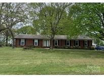 Charming single-story brick home nestled amidst mature trees on a well-manicured lawn at 8616 Fallsdale Dr, Charlotte, NC 28214
