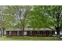 Charming brick home featuring a well-manicured lawn and mature trees providing ample shade at 8616 Fallsdale Dr, Charlotte, NC 28214