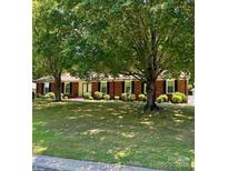 Charming brick home with black shutters and mature trees in the front yard at 8616 Fallsdale Dr, Charlotte, NC 28214