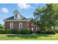 Charming red brick home featuring a lush front lawn and mature trees, creating a welcoming curb appeal at 104 Fairwind Ct, Fort Mill, SC 29708