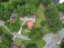 Stunning aerial view of a charming home with a bright red roof surrounded by lush greenery and mature trees at 1614 Linwood Rd, Gaston, NC 28052