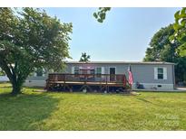 Charming single-story home with a large front yard, inviting deck, and American flag, perfect for Gathering gatherings at 2449 Leonhardt Rd, Cherryville, NC 28021