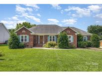 Charming red brick home featuring a well-manicured lawn, lovely landscaping, and appealing exterior design at 2627 Willis Dr, Harrisburg, NC 28075