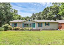 Charming single-story home with a well-maintained lawn, blue shutters, and mature trees in a serene, residential neighborhood at 4104 Pebblebrook Sw Cir, Concord, NC 28027