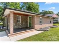 Charming single-story home featuring brick and stone accents, a covered porch, and a well-manicured lawn at 1116 S Juniper St, Kannapolis, NC 28081