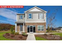 Charming two-story home featuring stone accents, gray siding, manicured lawn, and inviting front entrance at 1373 Zermatt Ct, Monroe, NC 28112