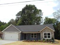 Charming single-story home featuring stone accents, a modern garage door, and beautiful landscaping at 1802 Cooper Ave, Kannapolis, NC 28081
