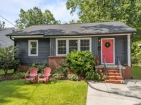 Charming home featuring a landscaped yard, gray siding, and a welcoming red front door at 309 Ackert Ave, Salisbury, NC 28144