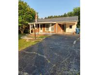 Charming brick home featuring a metal roof, attached carport, and well-maintained landscaping at 490 S Moose Rd, Mount Pleasant, NC 28124